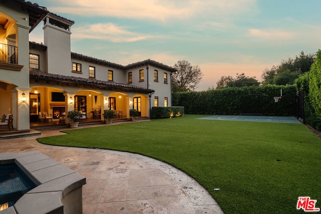 back house at dusk featuring a fenced in pool, a balcony, a yard, and a patio