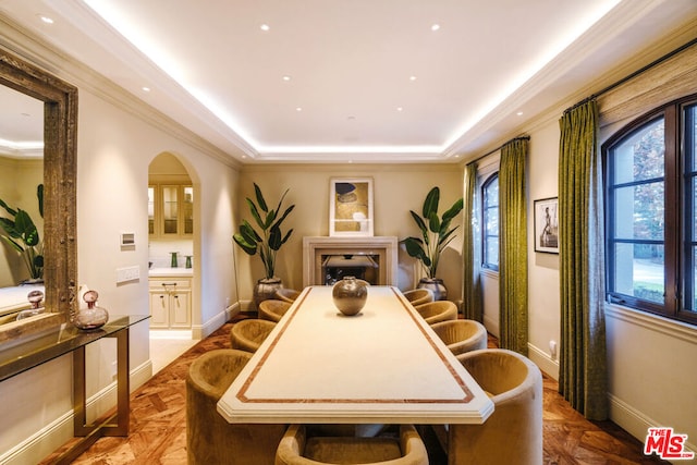 dining room with parquet flooring, a tray ceiling, and ornamental molding