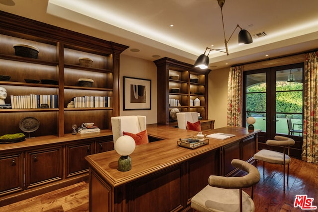 office area with light wood-type flooring, french doors, a tray ceiling, and built in desk