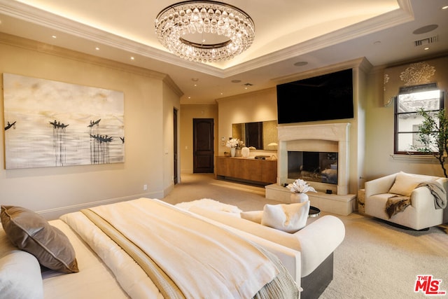 carpeted bedroom featuring crown molding, a fireplace, a tray ceiling, and an inviting chandelier