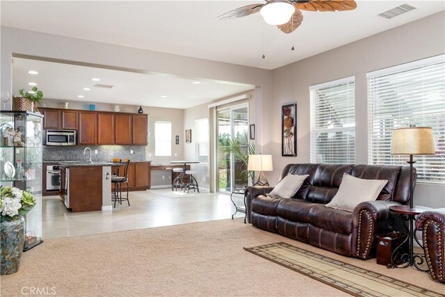 living room featuring ceiling fan, sink, and light tile patterned floors