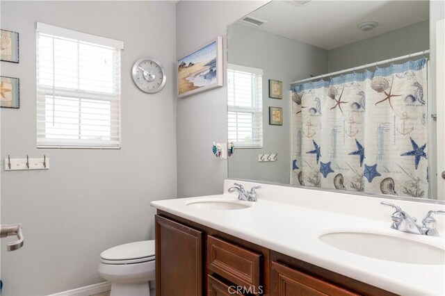 bathroom with toilet, vanity, plenty of natural light, and curtained shower