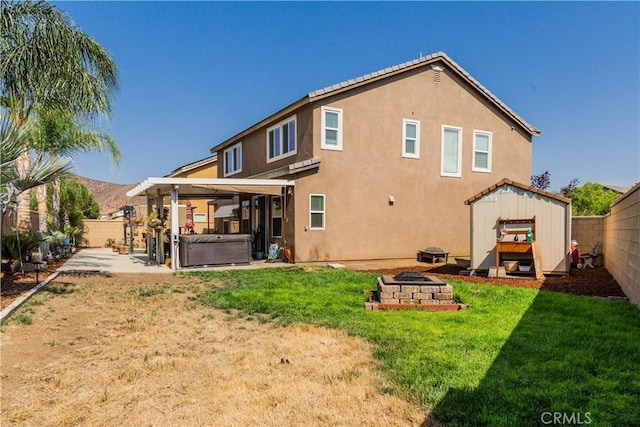 rear view of property with a hot tub, a patio area, and a fire pit