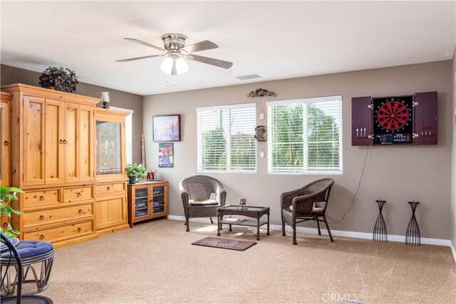 living area featuring light carpet and ceiling fan