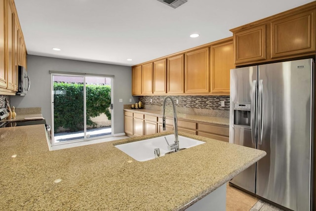 kitchen with tasteful backsplash, kitchen peninsula, sink, appliances with stainless steel finishes, and light stone counters