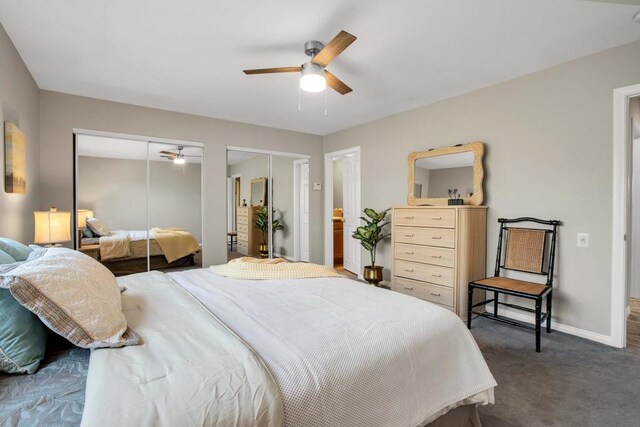 bedroom featuring ceiling fan, two closets, and dark carpet