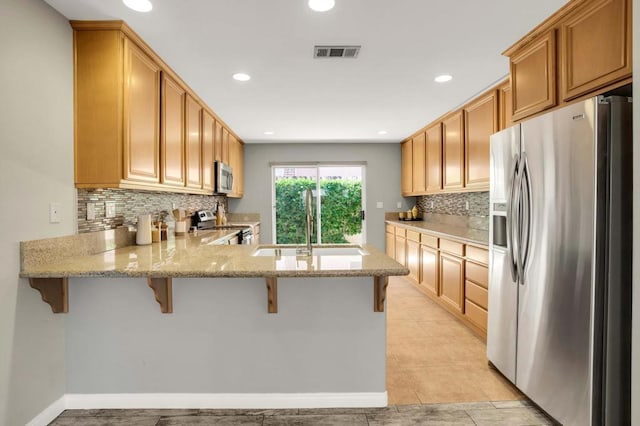 kitchen with decorative backsplash, sink, appliances with stainless steel finishes, and kitchen peninsula