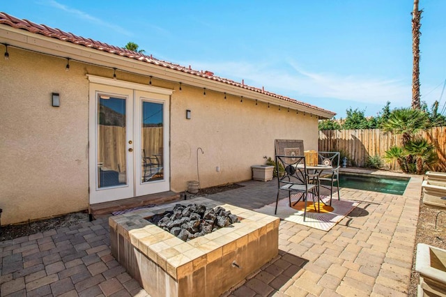 view of patio / terrace with an outdoor fire pit, french doors, and a fenced in pool