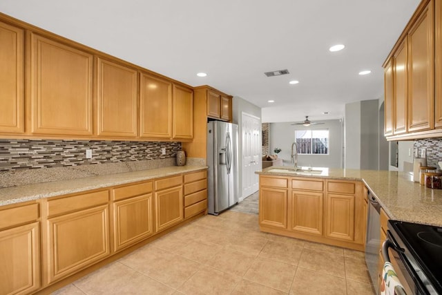 kitchen featuring light stone countertops, appliances with stainless steel finishes, tasteful backsplash, sink, and ceiling fan