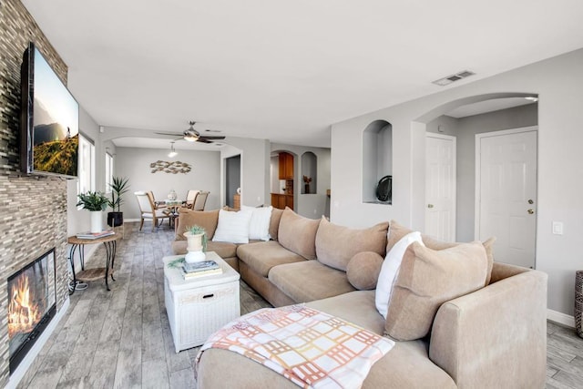 living room with ceiling fan, light hardwood / wood-style flooring, and a fireplace