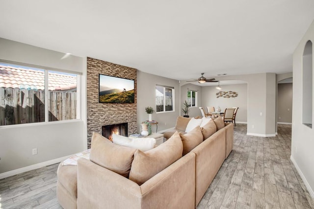 living room with ceiling fan, a fireplace, and light hardwood / wood-style floors