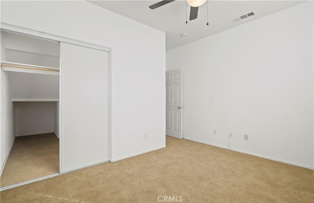 unfurnished bedroom featuring light carpet, ceiling fan, and a closet