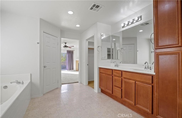 bathroom with tiled bath, vanity, and ceiling fan