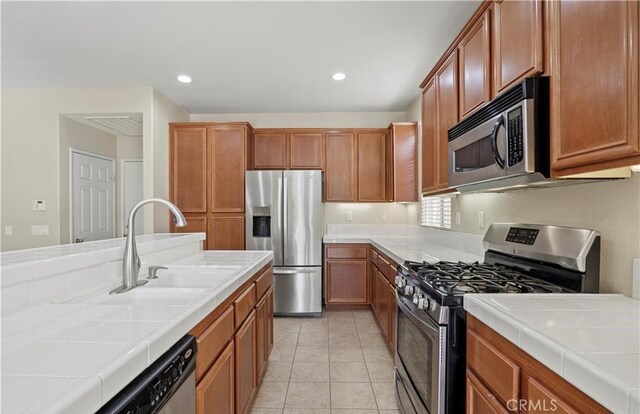 kitchen featuring sink, stainless steel appliances, tile countertops, and light tile patterned flooring