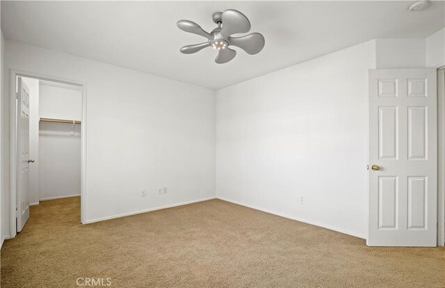 unfurnished bedroom with a spacious closet, ceiling fan, a closet, and light carpet