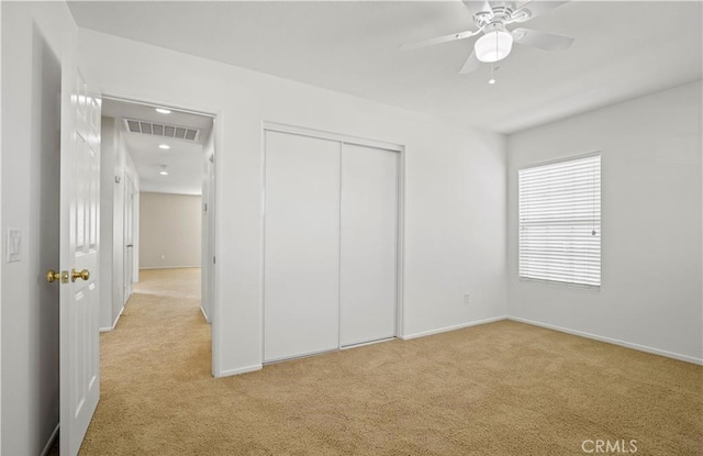 unfurnished bedroom with ceiling fan, light colored carpet, and a closet