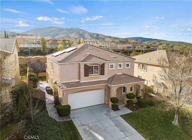 mediterranean / spanish-style home with stucco siding, a tile roof, a gate, fence, and a mountain view