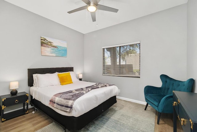 bedroom with ceiling fan, light hardwood / wood-style flooring, and vaulted ceiling