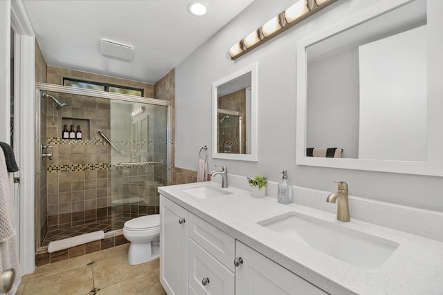 bathroom featuring tile patterned floors, a shower with door, toilet, and vanity