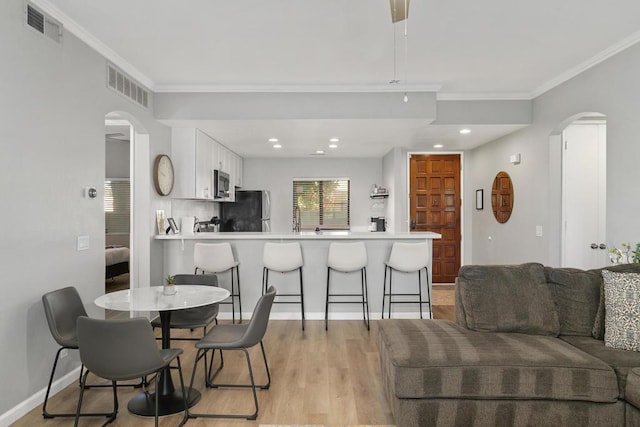 dining space featuring ornamental molding and light hardwood / wood-style floors