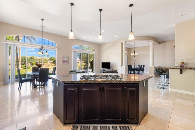 kitchen with hanging light fixtures, stainless steel gas cooktop, a notable chandelier, and dark brown cabinets