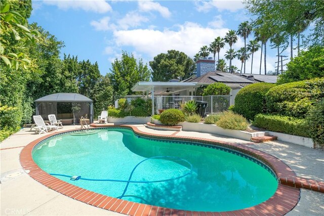 view of swimming pool with ceiling fan and a patio