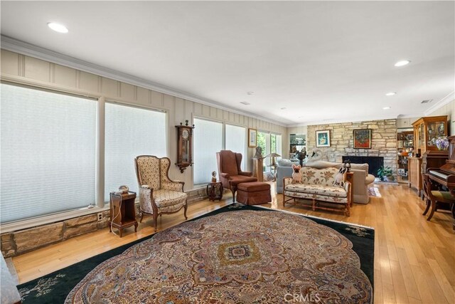 living room with hardwood / wood-style flooring, ornamental molding, and a fireplace