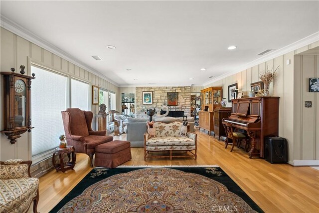 living room featuring light hardwood / wood-style floors, ornamental molding, and a fireplace