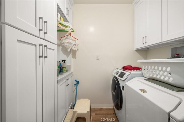 laundry area featuring hardwood / wood-style flooring, cabinets, and washer and clothes dryer