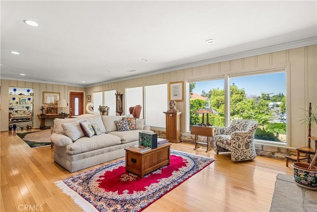 living room with a healthy amount of sunlight, light wood-type flooring, and ornamental molding