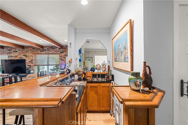 bar featuring light wood-type flooring and beamed ceiling