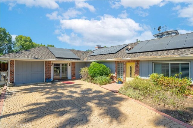 single story home featuring a garage and solar panels