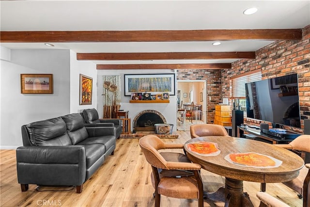 living room with beam ceiling, light wood-type flooring, a brick fireplace, and brick wall