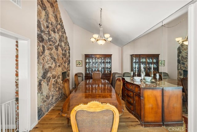 dining area featuring light hardwood / wood-style flooring, an inviting chandelier, and vaulted ceiling