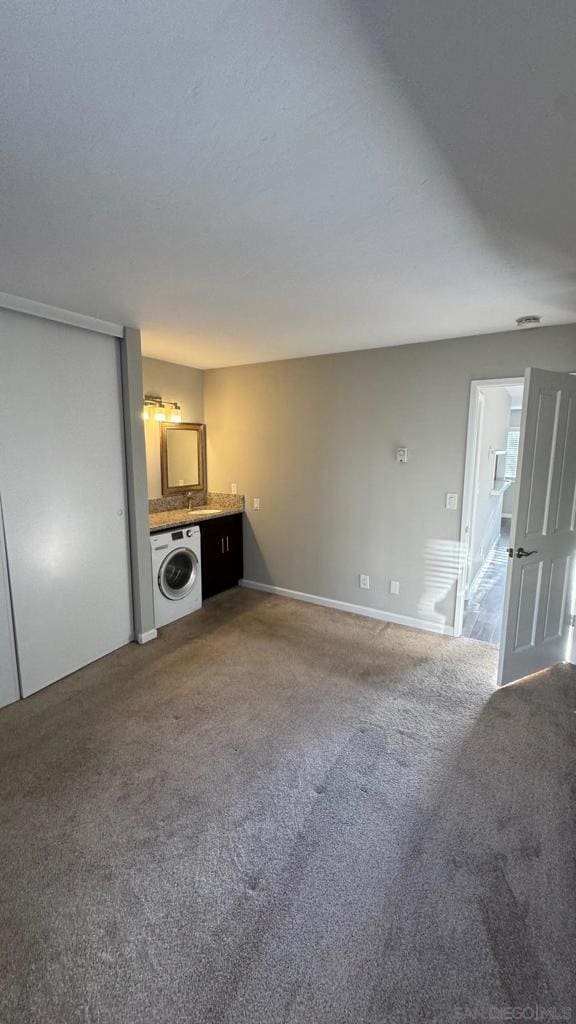 unfurnished living room featuring carpet and washer / dryer