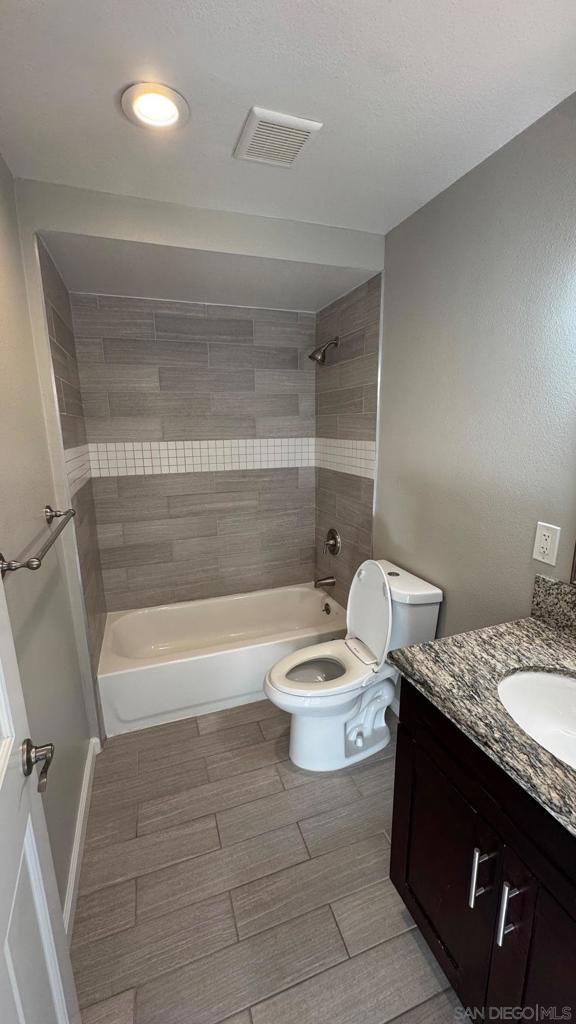 full bathroom with toilet, vanity, and tiled shower / bath combo