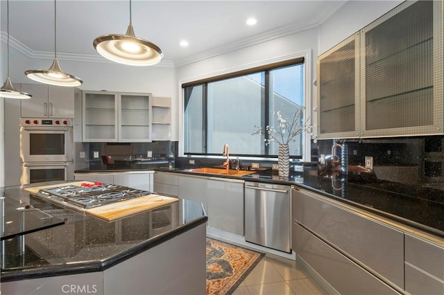 kitchen featuring stainless steel appliances, tasteful backsplash, light tile patterned flooring, hanging light fixtures, and sink