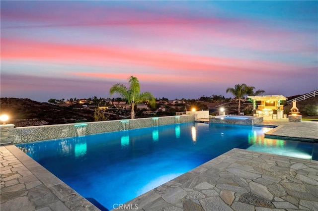 pool at dusk featuring pool water feature, area for grilling, an in ground hot tub, and a patio