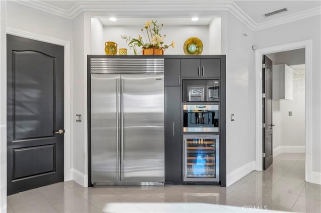 kitchen featuring light tile patterned floors, appliances with stainless steel finishes, beverage cooler, and ornamental molding