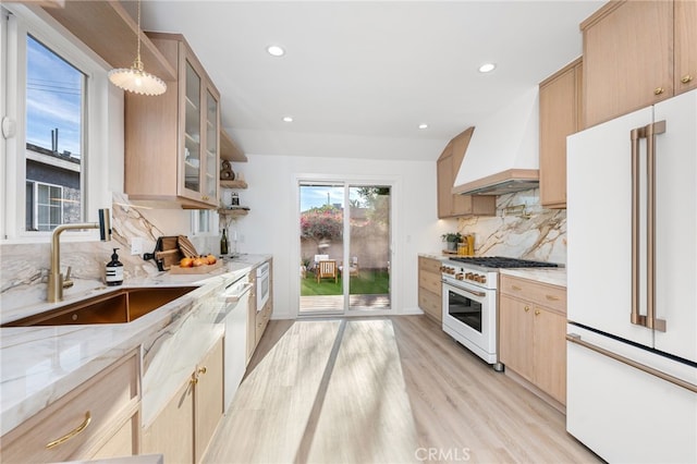 kitchen with pendant lighting, high end appliances, sink, light hardwood / wood-style flooring, and custom range hood