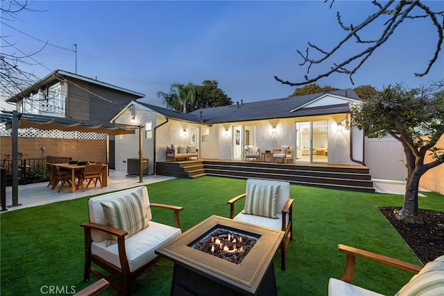 back house at dusk featuring a patio area, a fire pit, a yard, cooling unit, and a wooden deck