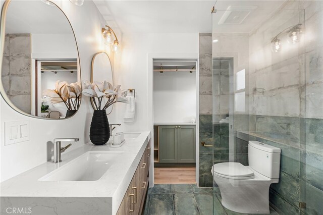 bathroom with toilet, a shower, tile walls, and vanity