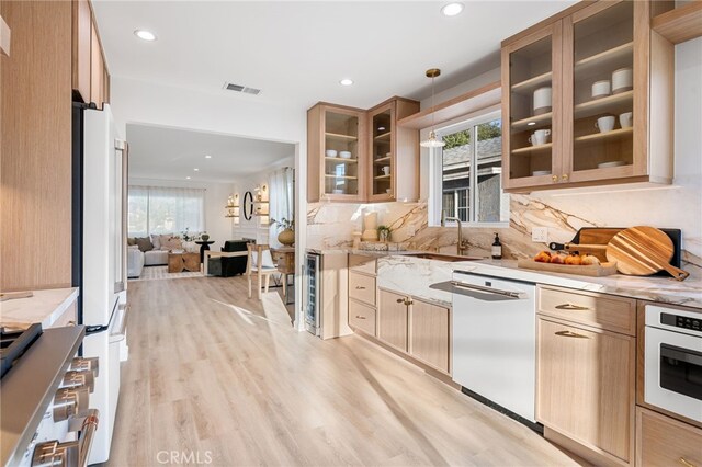 kitchen with a wealth of natural light, decorative light fixtures, light stone counters, and white appliances