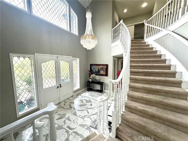 foyer featuring an inviting chandelier and a towering ceiling