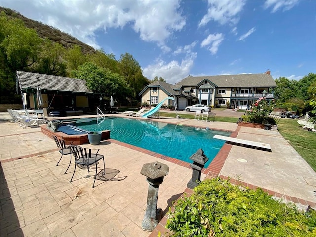 view of swimming pool featuring a diving board, a patio area, and a water slide