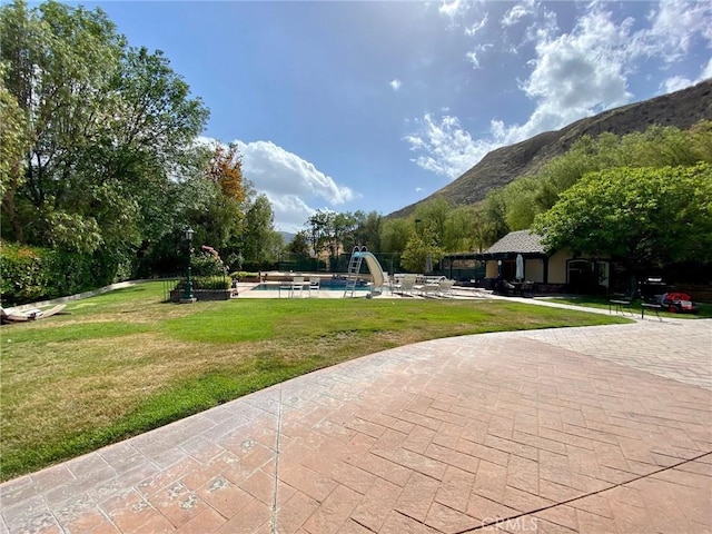 view of community with a yard, a patio, a mountain view, and a swimming pool