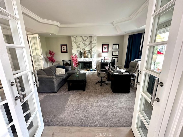 office area with a tray ceiling, a fireplace, french doors, carpet flooring, and crown molding