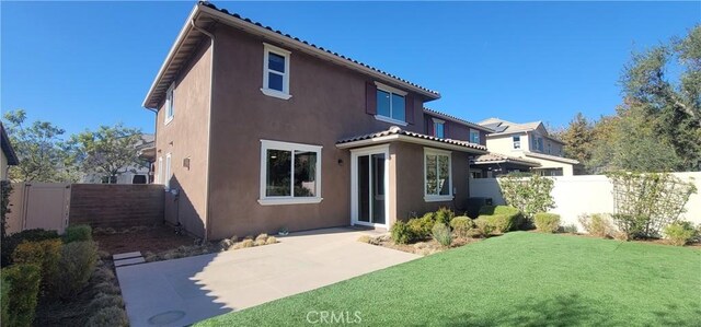 rear view of property with a lawn and a patio area