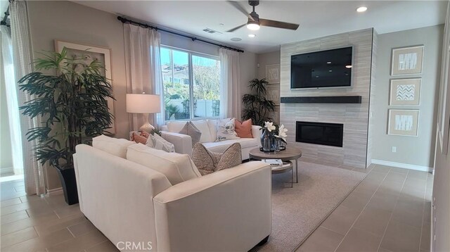 tiled living room with ceiling fan and a tile fireplace