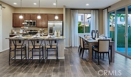 kitchen featuring decorative light fixtures, a barn door, a kitchen island with sink, a breakfast bar area, and stainless steel appliances